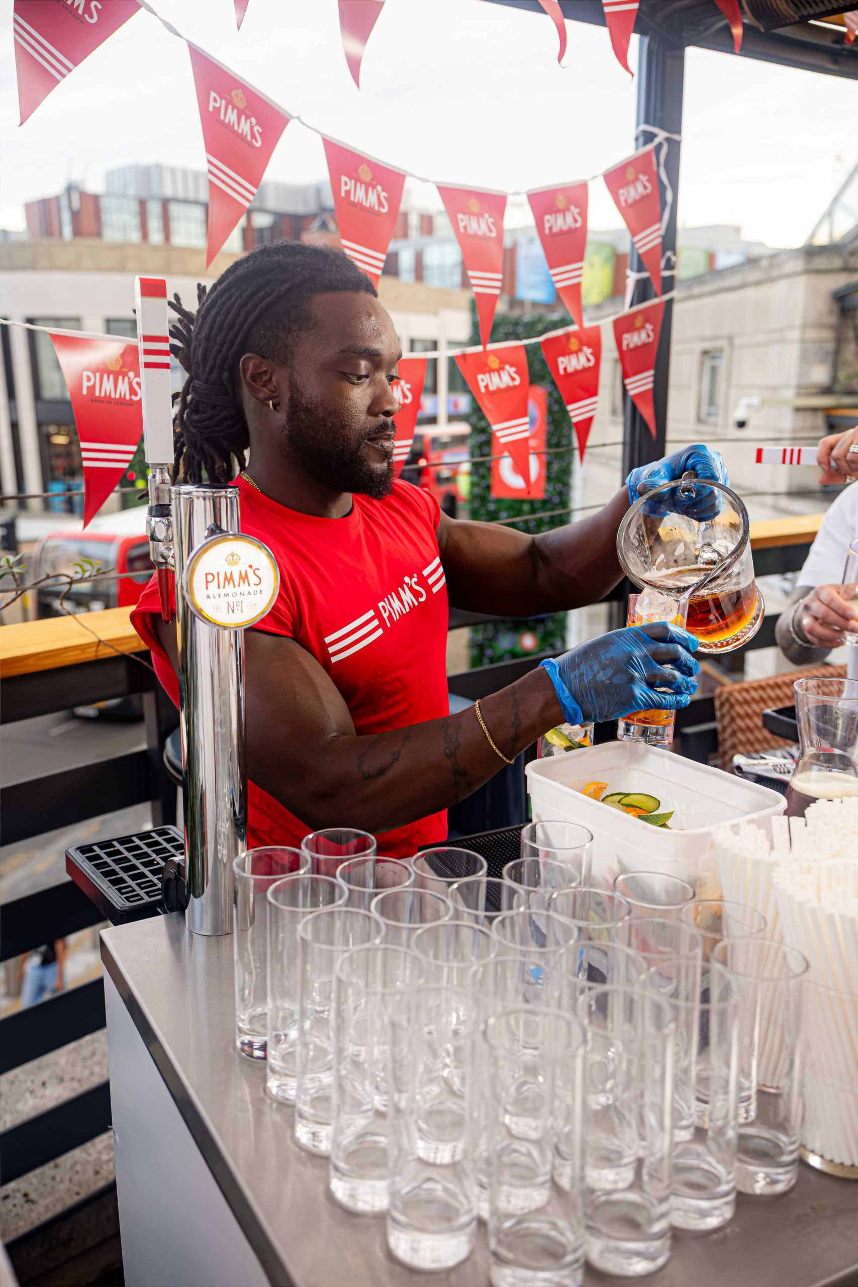 Bar man serving Pimms at bar with view